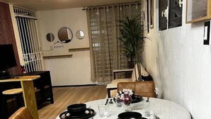 Uma área de refeições com uma mesa redonda posta para quatro pessoas, rodeada por quatro cadeiras.