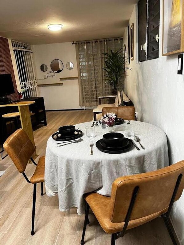 Comedor con una mesa redonda dispuesta para cuatro personas, rodeada por cuatro sillas.