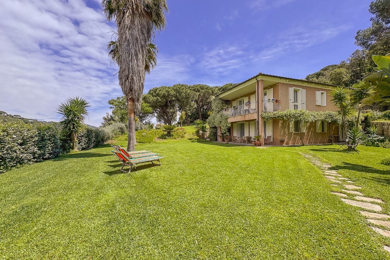 A two-story house with a balcony, surrounded by a well-maintained lawn and garden.