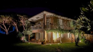 A two-story house with a balcony, surrounded by lush greenery and a well-maintained lawn. - Suite with sea view and private woodland (Capoliveri)