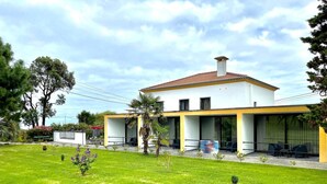A modern two-story house with a flat roof, large windows, and a well-maintained lawn.
