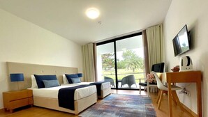 A hotel room with a bed, a desk, a chair, a television, and a view of the outdoors.