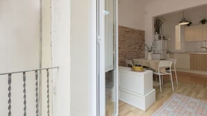Een interieur met een keuken, een eethoek en een schuifdeur naar een balkon.