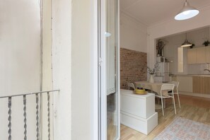 Ein Innenraum mit Küche, Essbereich und einer Glastür, die auf einen Balkon führt.