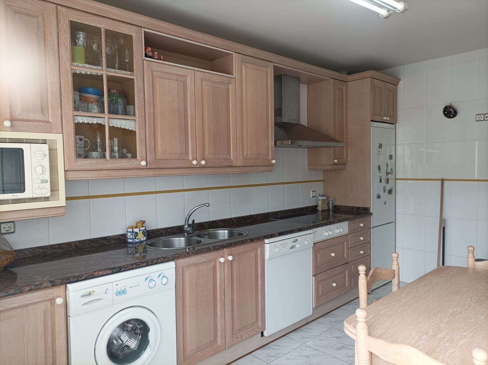 A kitchen with wooden cabinets, a built-in microwave, a dishwasher, and a washing machine.