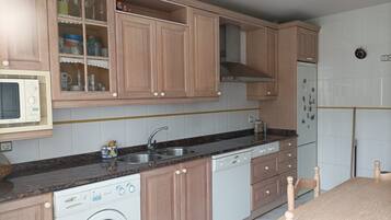A kitchen with wooden cabinets, a built-in microwave, a dishwasher, and a washing machine.