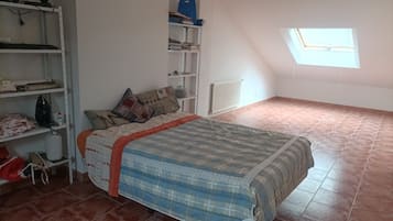 Ein Schlafzimmer mit Bett, Regalen, einer Heizung und einem Oberlicht.