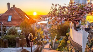 A residential street with houses, a wooden fence, and a clear view of the sunset. - Charming Seaside Apartment in Bergen With Stunning Views (Bergen)