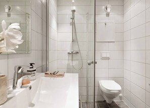 A modern bathroom with a glass-enclosed shower, a white sink with a soap dispenser, and a toilet. - Charming Seaside Apartment in Bergen With Stunning Views (Bergen)
