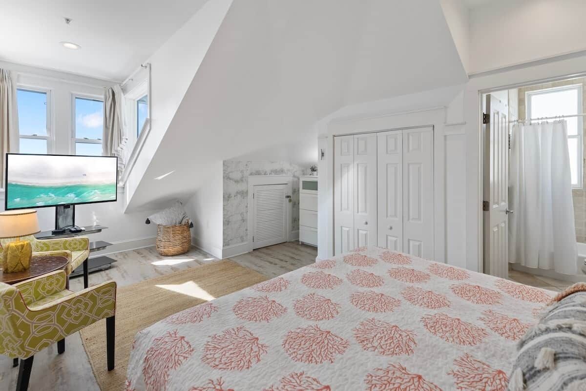 Un dormitorio con cama, televisión, escritorio y ventana.