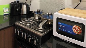 A kitchen with a stove, kettle, and microwave. - Kawe beach Apartments, get a clear city view of Dar es Salaam from your balcony (Dar es Salaam)
