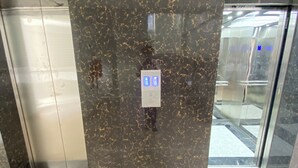 An elevator with a marble wall and a floor with a grid pattern. - Kawe beach Apartments, get a clear city view of Dar es Salaam from your balcony (Dar es Salaam)