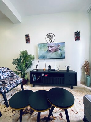 Un soggiorno con TV a parete, un mobile TV nero, un divano a fantasia e un tavolino.