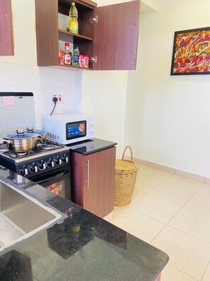 A kitchen with a stove, microwave, and a basket.