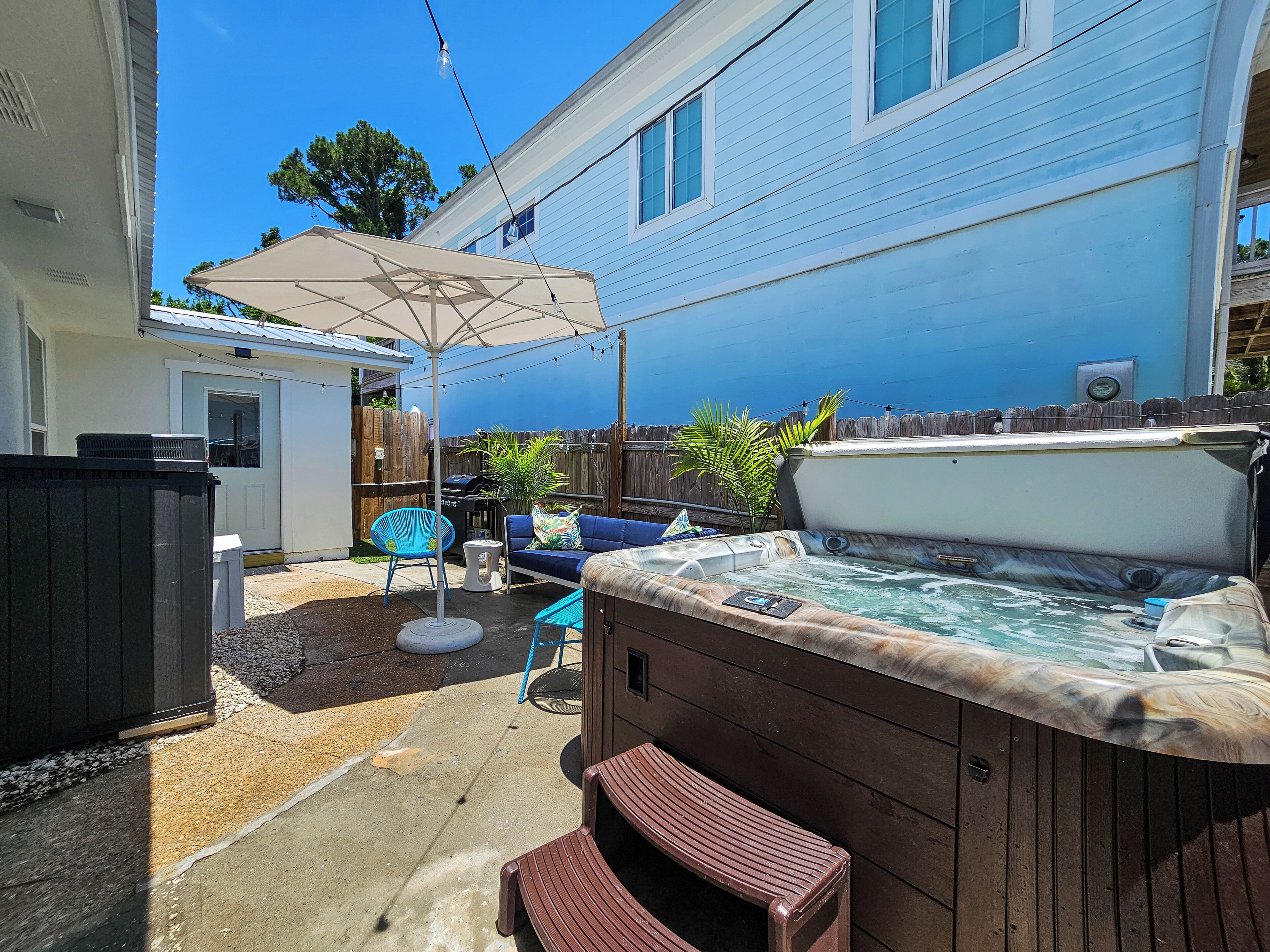 A backyard with a hot tub, patio furniture, and a wooden deck.