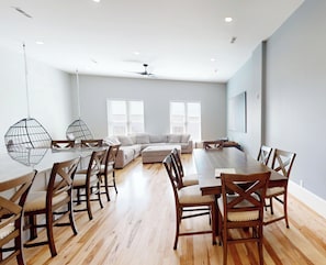 Un comedor moderno con una mesa y sillas de madera, un sofá y un ventilador de techo.