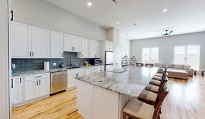 A modern kitchen with white cabinets, a granite countertop, and a stainless steel refrigerator.