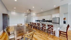 A spacious kitchen with white cabinets, a large island, and a dining area with wooden chairs.