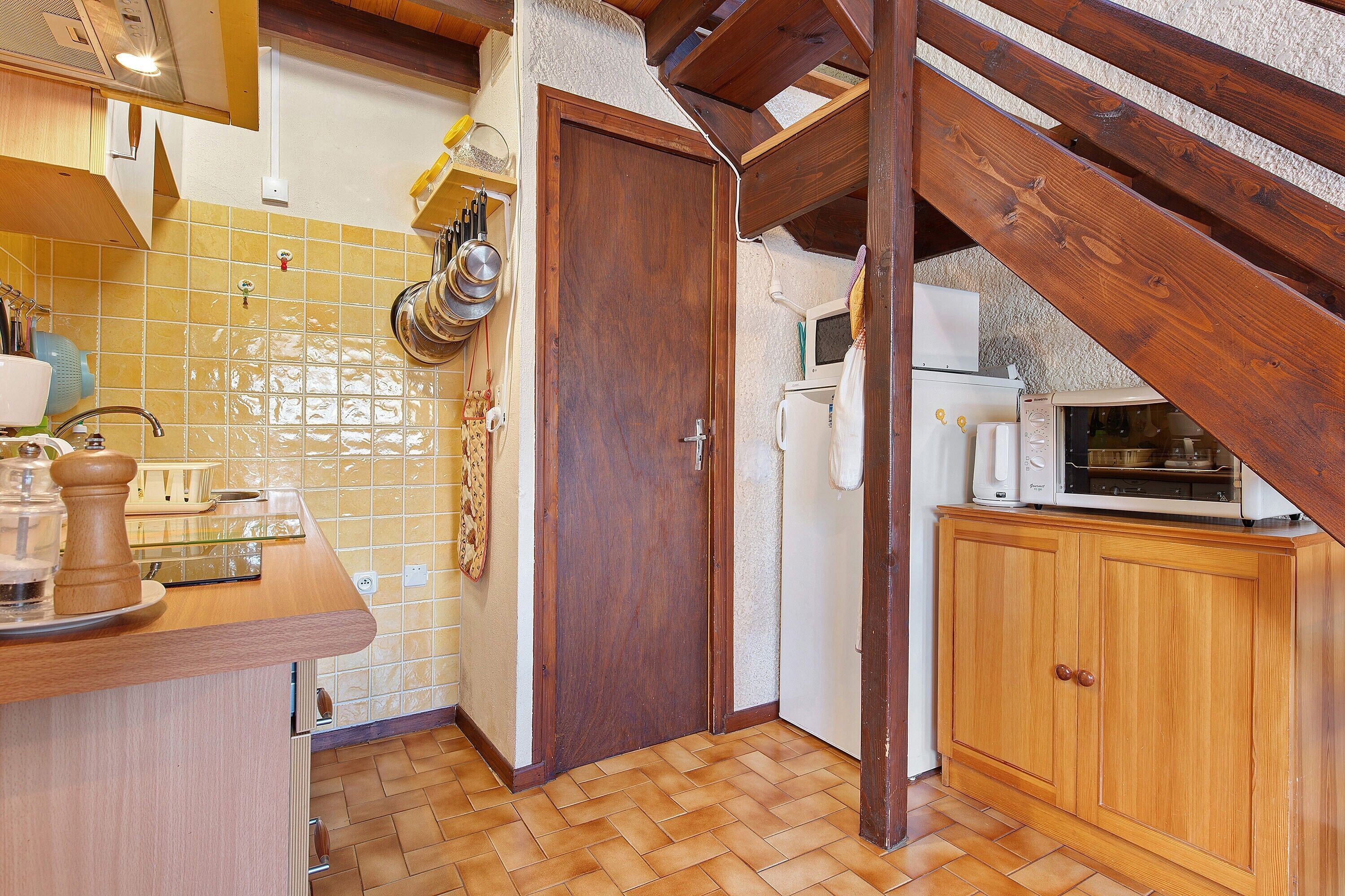 A kitchen with wooden cabinets, a tiled backsplash, and a wooden ceiling.