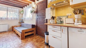Eine kompakte Küche mit Holzschränken, einem eingebauten Geschirrspüler und einem Fenster mit Vorhängen.