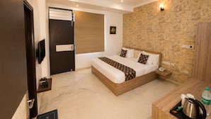 A hotel room with a bed, a desk with a kettle, a water bottle, and a phone. - Hotel The White Tulip (Jaipur)