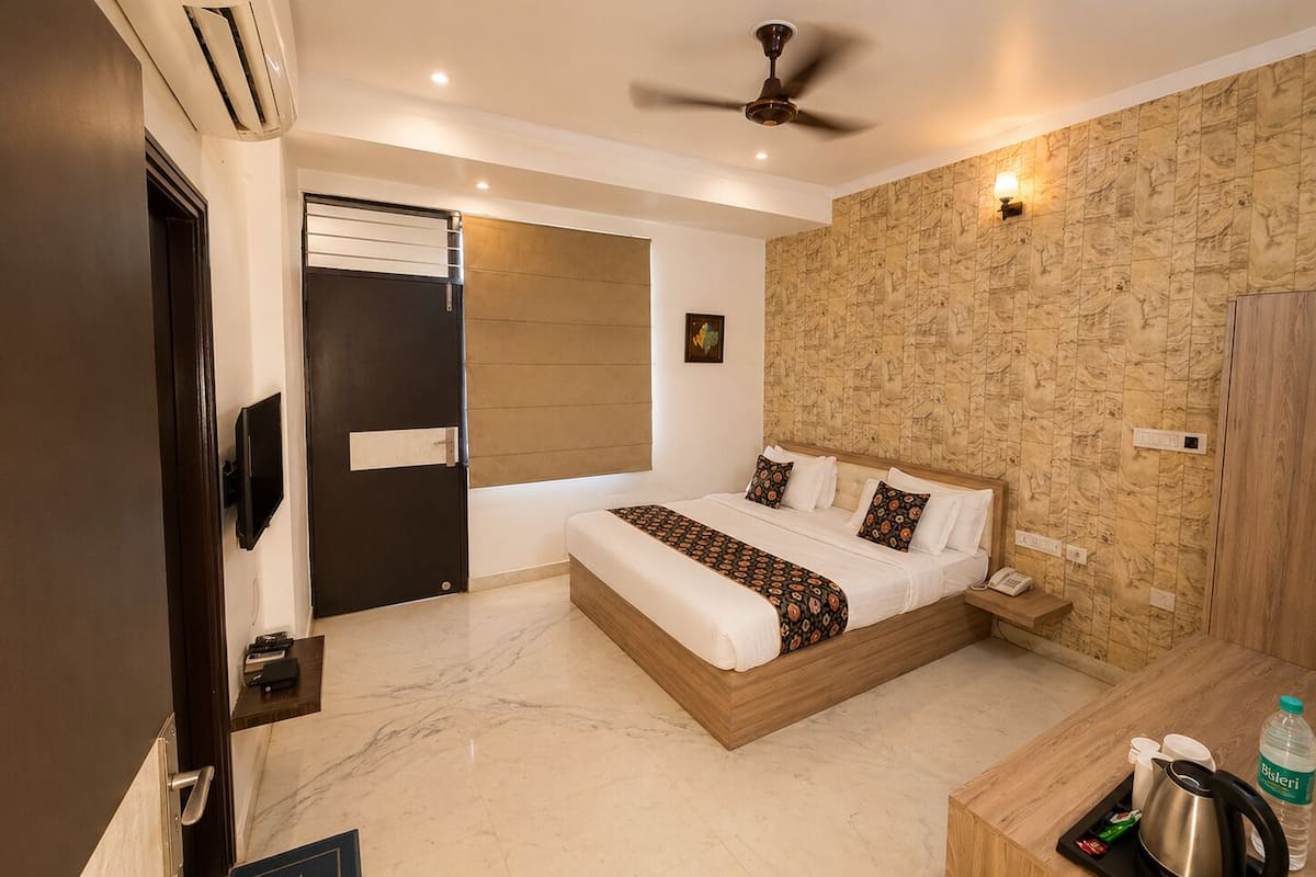 Una habitación de hotel con una cama, un escritorio con hervidor, una botella de agua y un teléfono.