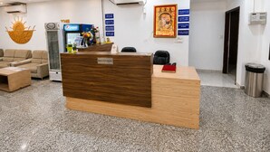 Un mostrador de recepción con detalles de madera, un refrigerador Pepsi, un aire acondicionado de pared y un ventilador de techo.