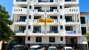 Un hotel de varios pisos con recepción en la planta baja, balcones en cada nivel y un cartel que dice 'Hotel The White Tulip'.