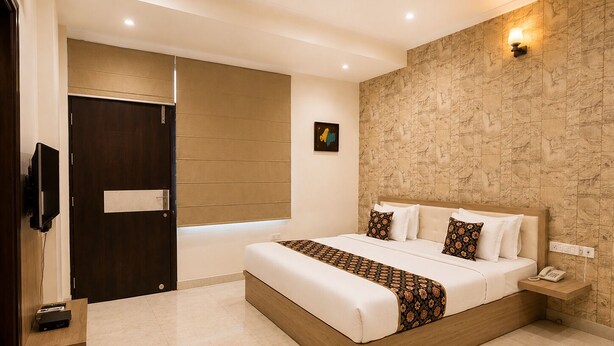 Una habitación de hotel moderna con una cama grande, una mesita de noche con teléfono, una lámpara de pared y una puerta con panel corredera.