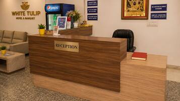 En receptionsdisk med en skylt som visar ”RECEPTION”, ett kylskåp med Pepsi, en inramad bild av en gudomlighet och en skylt som säger ”INGA BESÖKARE TILLÅTS I RUMMEN”.