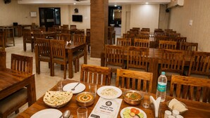 Un comedor de hotel con varias mesas y sillas de madera, una tarjeta de menú y una botella de agua.