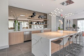 A modern kitchen with a marble island, bar stools, and pendant lighting. - Modern 2BR Residence with open views & Balcony (Doral)