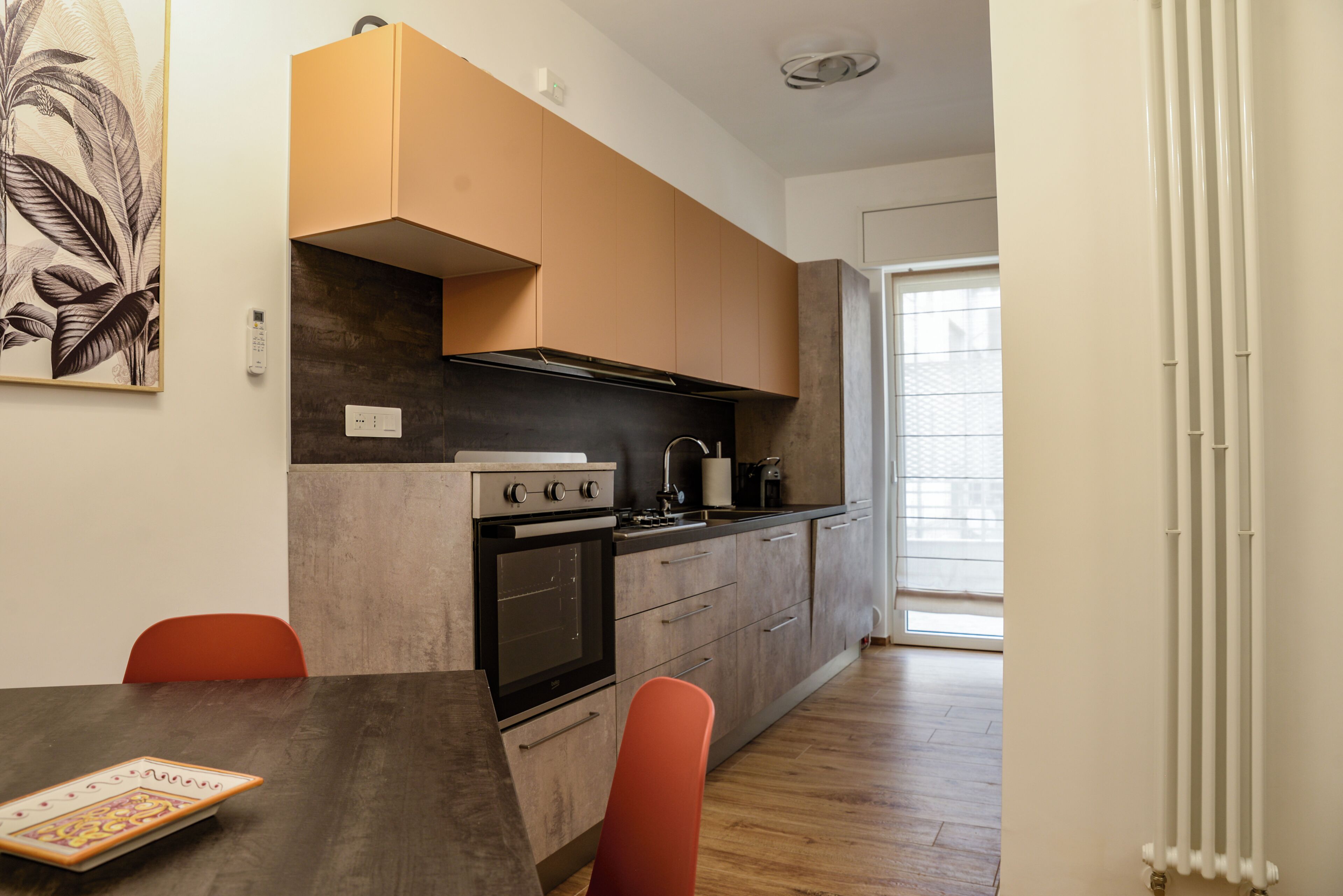 A modern kitchen with a stove, oven, and sink, wooden cabinets, and a dining table with chairs.