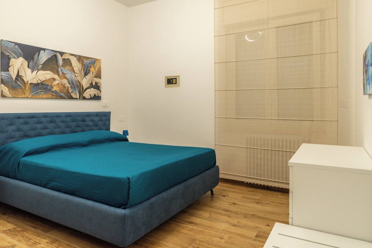 Un dormitorio con cama, un cuadro en la pared y un radiador.