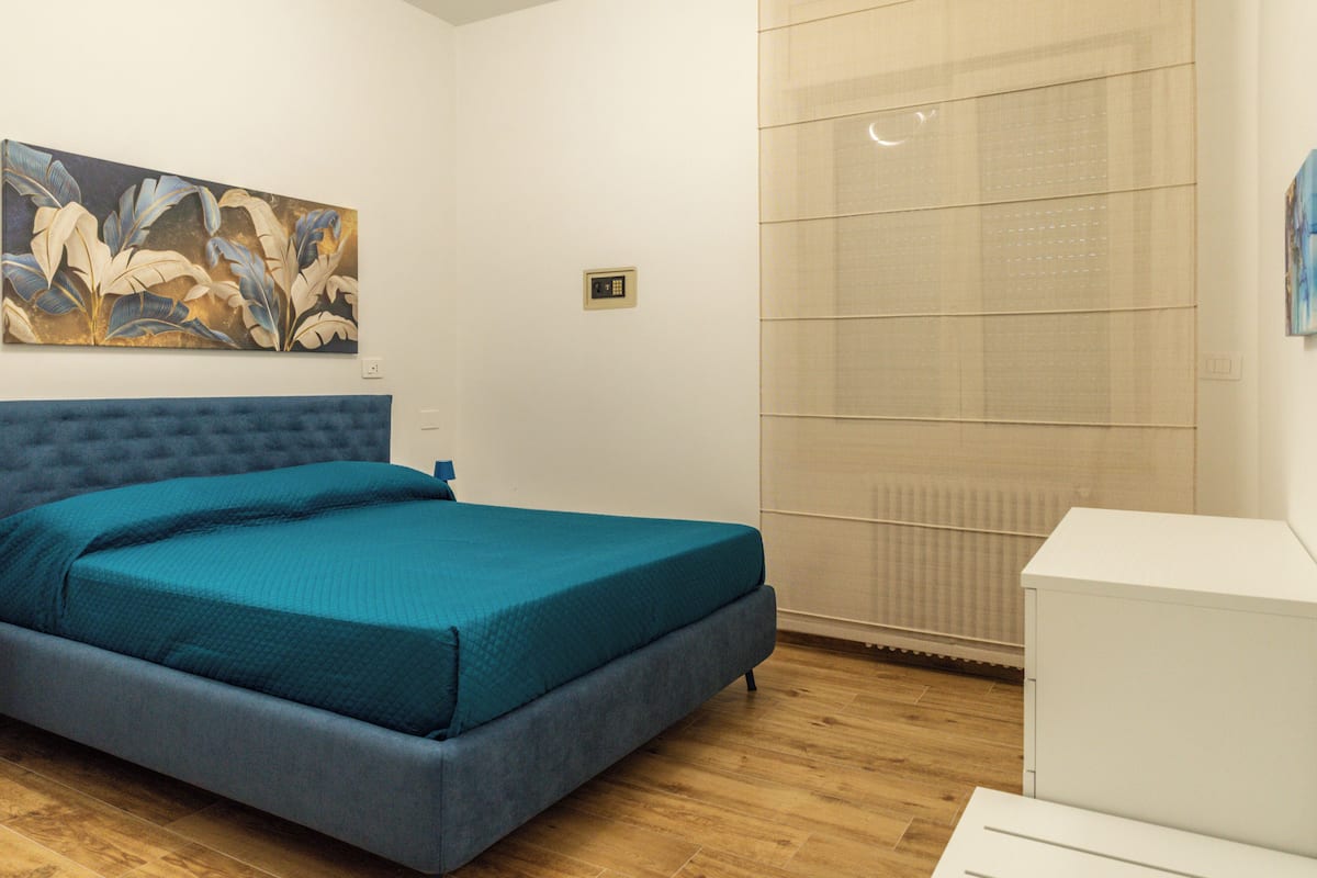 Une chambre à coucher avec un lit, un tableau au mur et un radiateur.