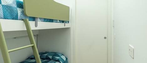 Una cama litera con escalera, una puerta y un enchufe en la pared.