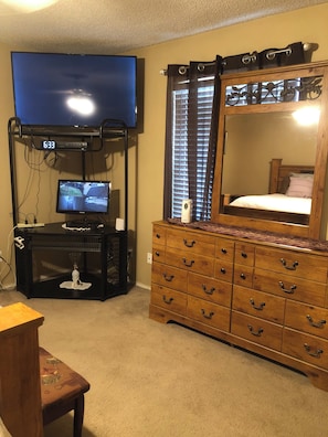 Ein Schlafzimmer mit Fernseher, Kommode und einer Uhr.