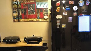 Eine Küche mit einem Kühlschrank, einer Kaffeemaschine und einem Wandbild.