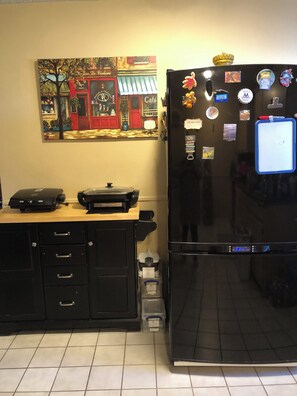 Eine Küche mit einem Kühlschrank, einer Kaffeemaschine und einem Wandbild.