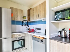 Eine moderne Küche mit Edelstahlgeräten, Holzschränken und blauen und weißen Fliesen.