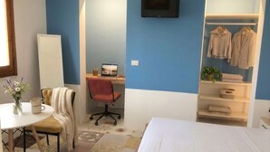 A bedroom with a bed, a desk with a laptop, a chair, a TV, and a wardrobe. - Aqua Home Area – Aqua Ground (Porto Cesareo)