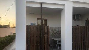 A patio area with a wooden fence, a table, and an air conditioning unit. - Aqua Home Area – Aqua Ground (Porto Cesareo)