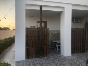 Eine Terrasse mit Holzzaun, Tisch und Klimaanlage.