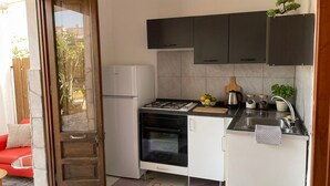 A compact kitchen with a gas stove, oven, and white cabinets. - Aqua Home Area – Aqua Ground (Porto Cesareo)