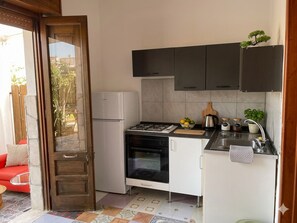 Eine kleine Küche mit Gasherd, Backofen und weißen Schränken.