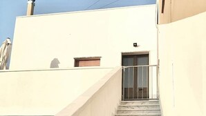 A marble staircase leading to a door with a metal railing, part of a building with a plain facade. - Aqua Home Area - Core Four (Porto Cesareo)