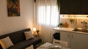 A modern kitchen with a dining area, a sofa, and a painting on the wall. - Aqua Home Area - Core Four (Porto Cesareo)
