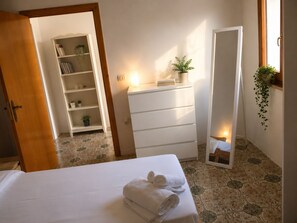 A hotel room with a bed, a dresser, a mirror, and a small shelf with plants. - Aqua Home Area - Core Four (Porto Cesareo)