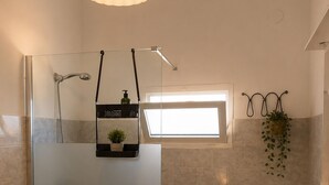 A modern bathroom with a glass shower enclosure, a toilet, a sink, and a small window providing natural light. - Aqua Home Area – Core Five (Porto Cesareo)
