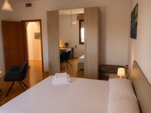 A hotel room with a bed, a desk, a chair, a bench, and a painting on the wall. - Aqua Home Area – Core Five (Porto Cesareo)